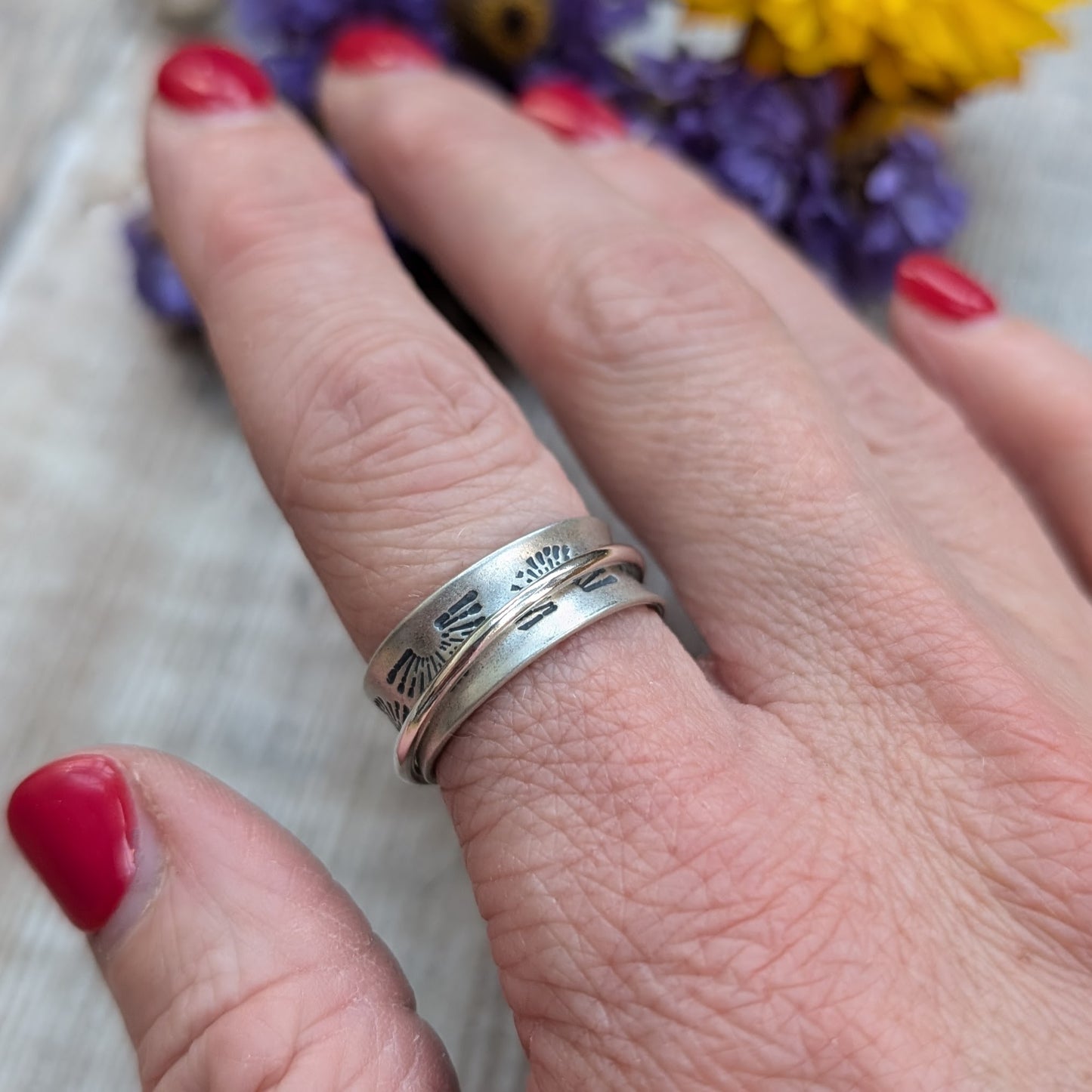Wide oxidised Sterling Silver band with stamped sunrise pattern. Additional 2mm wide silver band around the middle that spins independently.