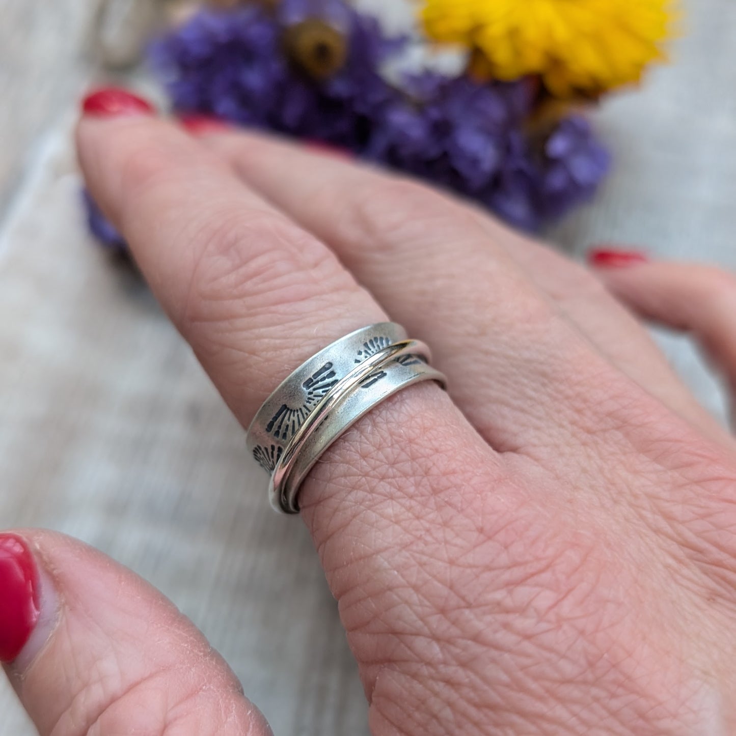 Wide oxidised Sterling Silver band with stamped sunrise pattern. Additional 2mm wide silver band around the middle that spins independently.