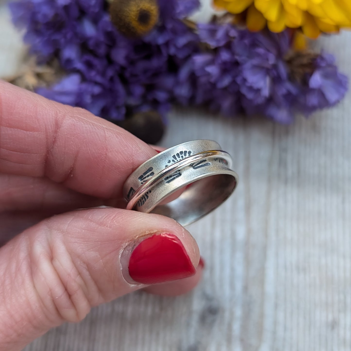 Wide oxidised Sterling Silver band with stamped sunrise pattern. Additional 2mm wide silver band around the middle that spins independently.