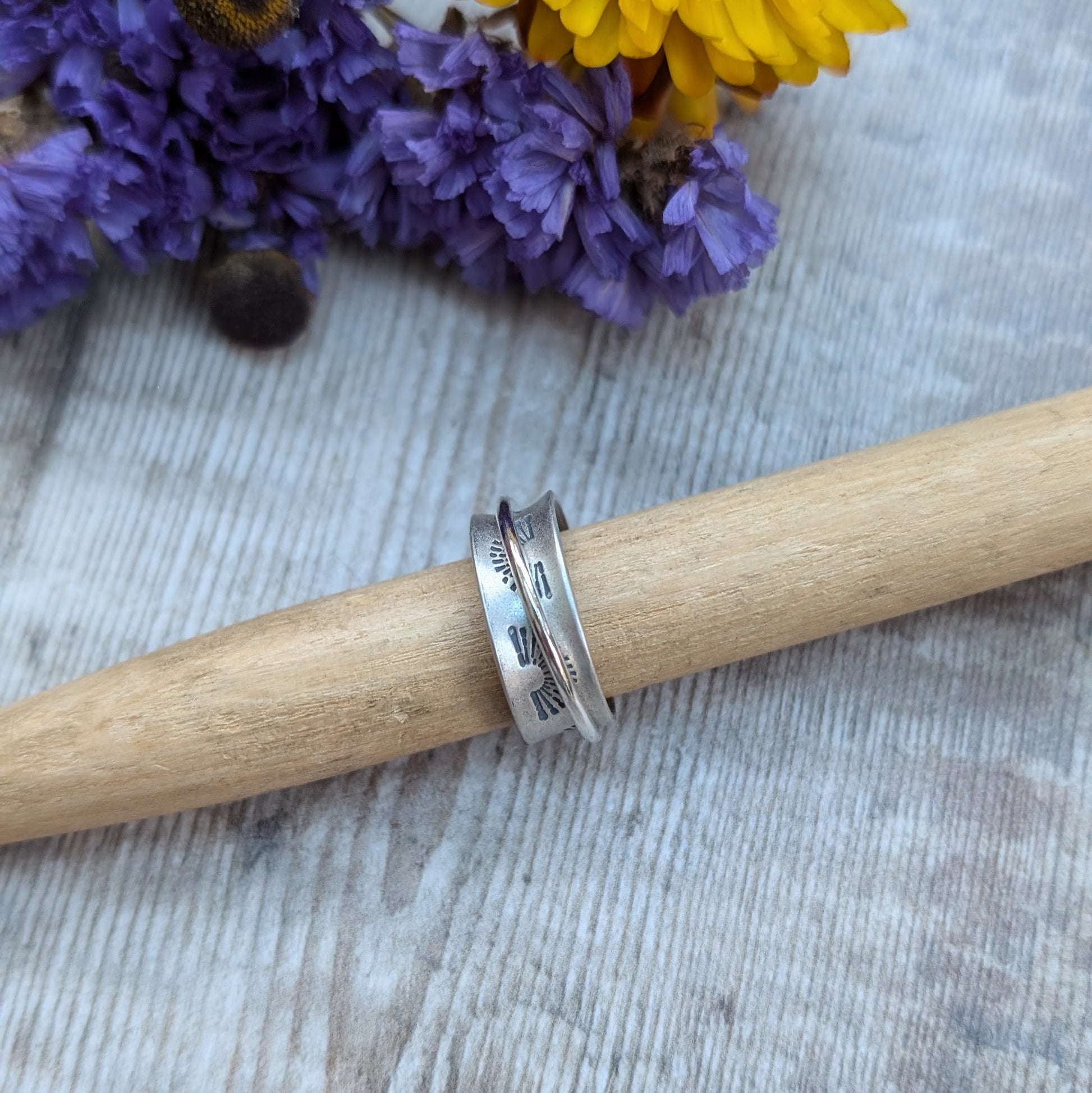 Wide oxidised Sterling Silver band with stamped sunrise pattern. Additional 2mm wide silver band around the middle that spins independently.