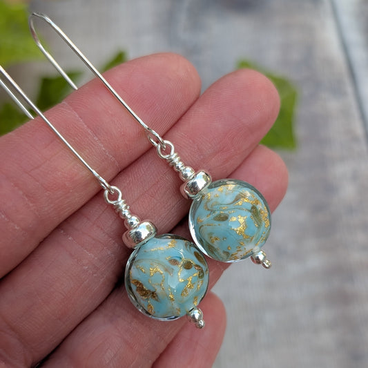 turquoise marbled Venetian glass long silver earrings held in a hand, showing the round handmade lampwork glass beads and silver details.
