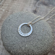Load image into Gallery viewer, Sterling Silver ‘WARRIOR’ necklace. Silver disc with offset hole in centre, looks like a thick circle. Attached via two small silver hoops to silver chain. On thicker part of disc, inscription wording hammered into the silver reads WARRIOR in capitals. Disc measures approximately 20 mm in diameter. Chain length 16, 18 or 20 inches.