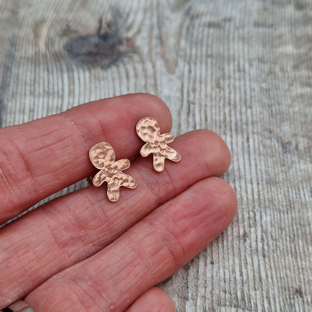 Copper gingerbread man shaped stud earrings set on sterling silver bars. Gingerbread man shape measures approximately 8mm x 12mm with hammered texture and two button indentations.