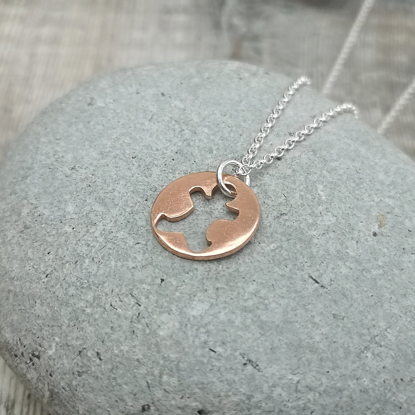 Round disc shaped copper pendant, approximately 15mm diameter. Traditional gingerbread man shape cut out from middle of circle. Attached to silver chain with small, round silver link through gingerbread man cut out.