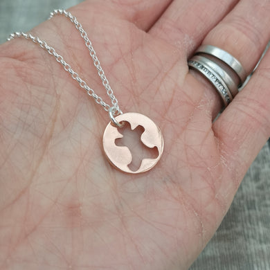 Round disc shaped copper pendant, approximately 15mm diameter. Traditional gingerbread man shape cut out from middle of circle. Attached to silver chain with small, round silver link through gingerbread man cut out.  