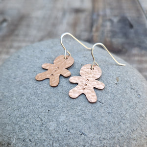 Copper gingerbread man shaped drop earrings set on sterling silver ear wires, drops approximately 30mm. Gingerbread man shape measures approximately 20mm with hammered texture and three button indentations.
