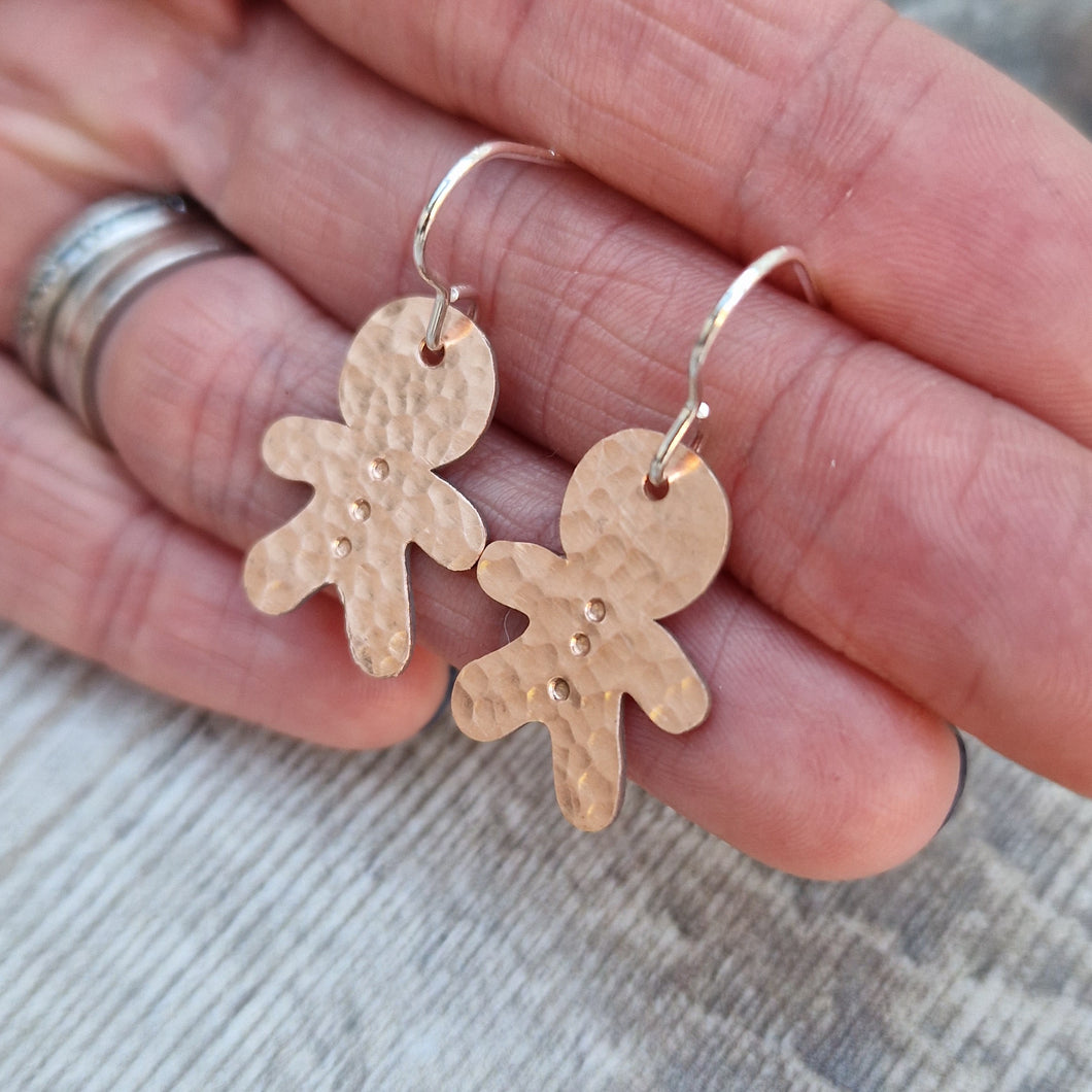 Copper gingerbread man shaped drop earrings set on sterling silver ear wires, drops approximately 30mm. Gingerbread man shape measures approximately 20mm with hammered texture and three button indentations.