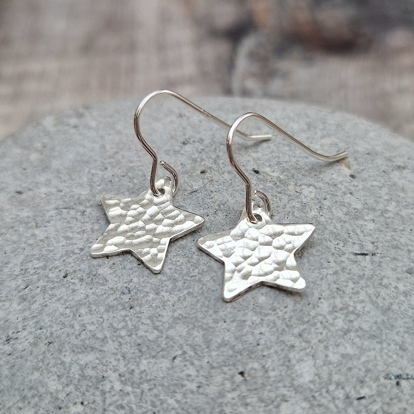 Each earring is a silver star shape with hammered texture finish suspended from silver earring wire.