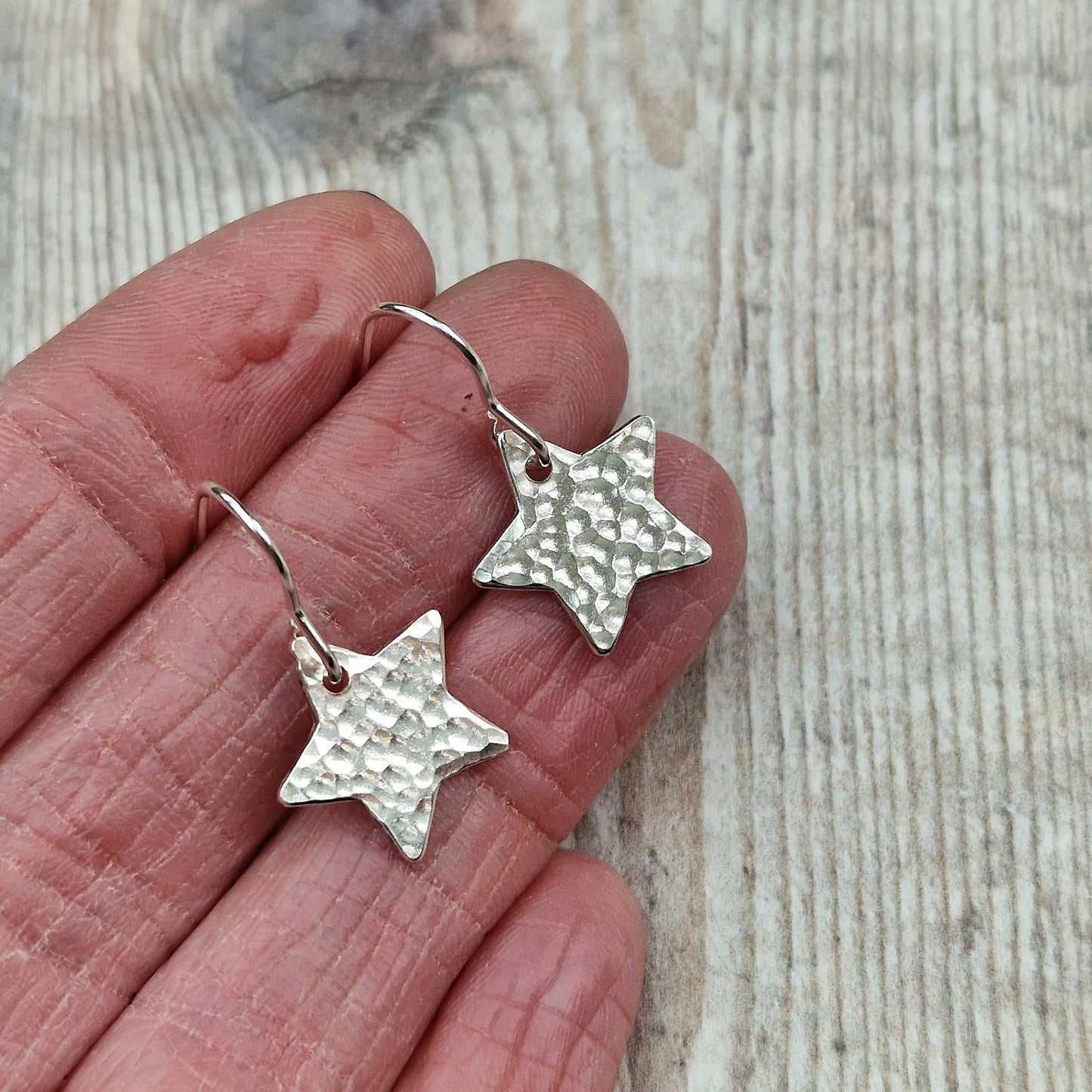 Each earring is a silver star shape with hammered texture finish suspended from silver earring wire.