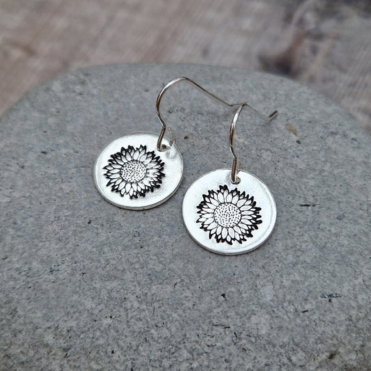 Each earring is a Sterling Silver disc suspended from silver earring wire. Each disc is stamped with a sunflower image.