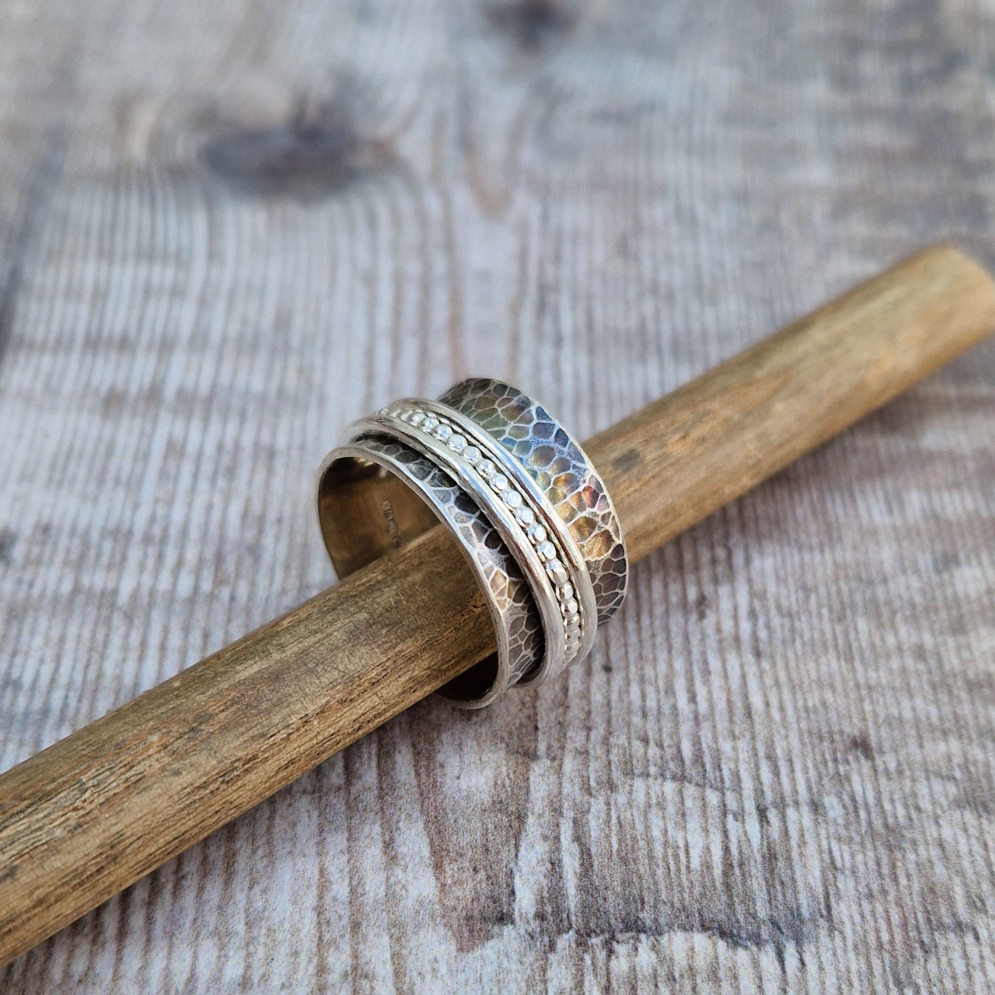 Approx. 8mm wide oxidised hammered texture silver band with three additional rings of beaded, smooth and delicate rope texture spinning independently around the middle.