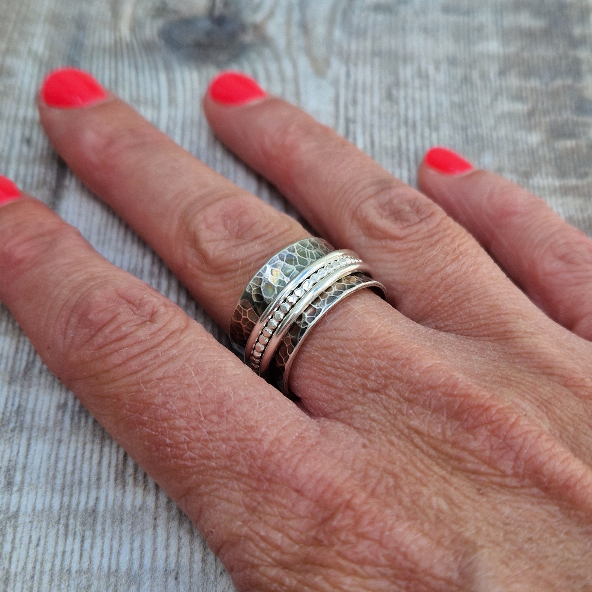 Approx. 8mm wide oxidised hammered texture silver band with three additional rings of beaded, smooth and delicate rope texture spinning independently around the middle.