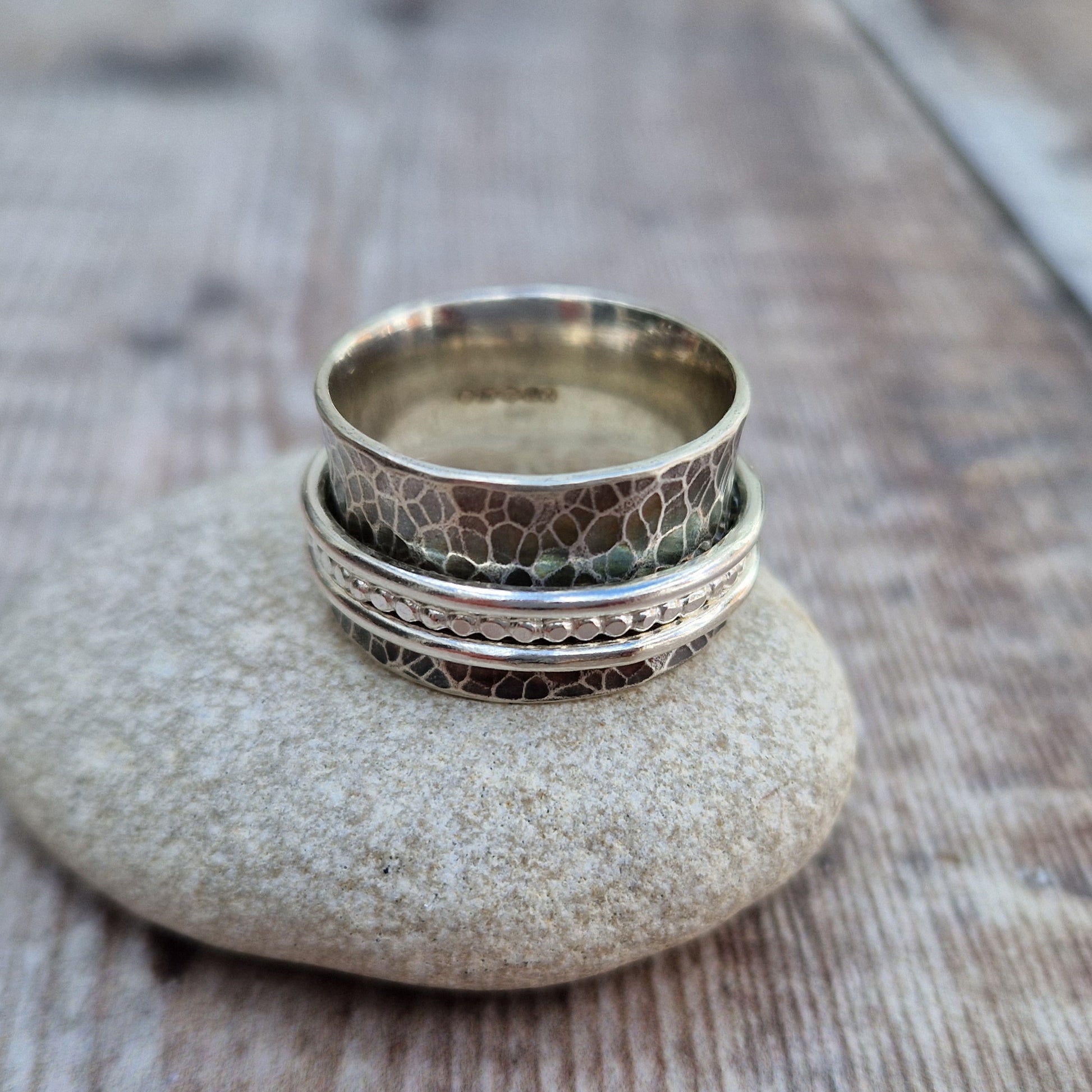 Approx. 8mm wide oxidised hammered texture silver band with three additional rings of beaded, smooth and delicate rope texture spinning independently around the middle.