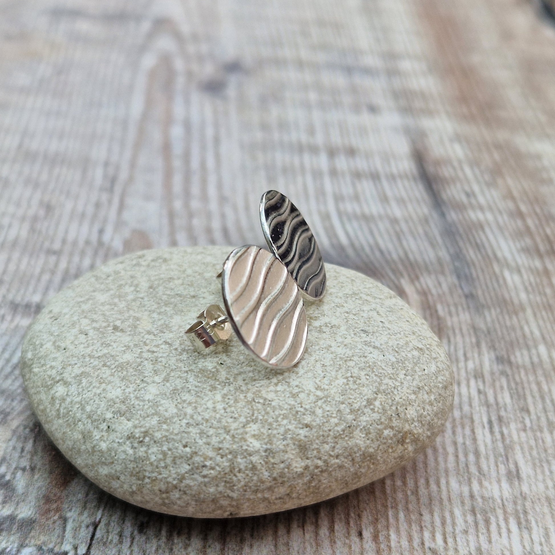 Each earring is a sterling silver disc stamped with a wavy line pattern. The wavy lines are spaced apart and raised from the disc, mounted on a silver stud bar.