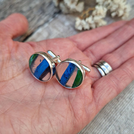 Silver Green and Blue Surfite cufflinks shown displayed on the palm of a hand. 