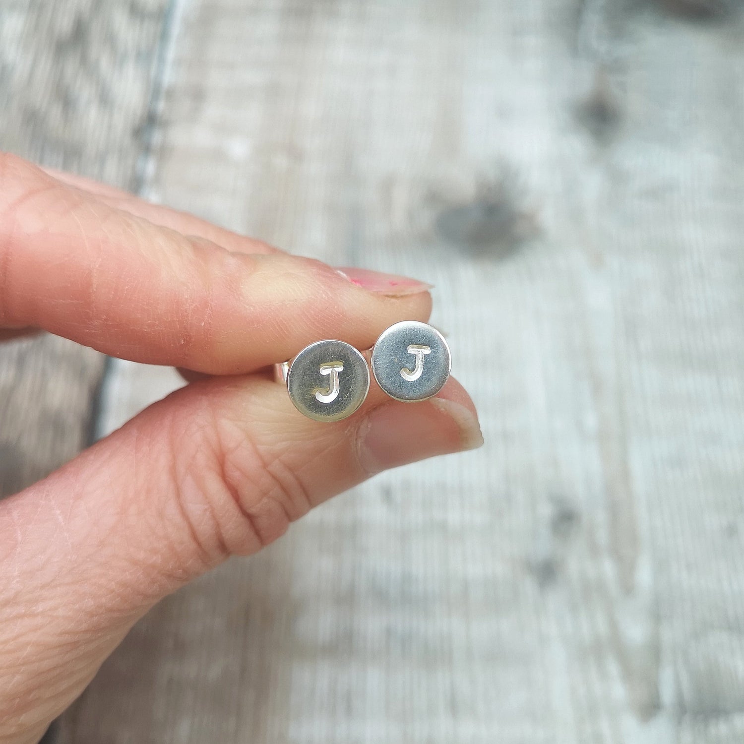 personalised jewellery shown held between two fingers. 