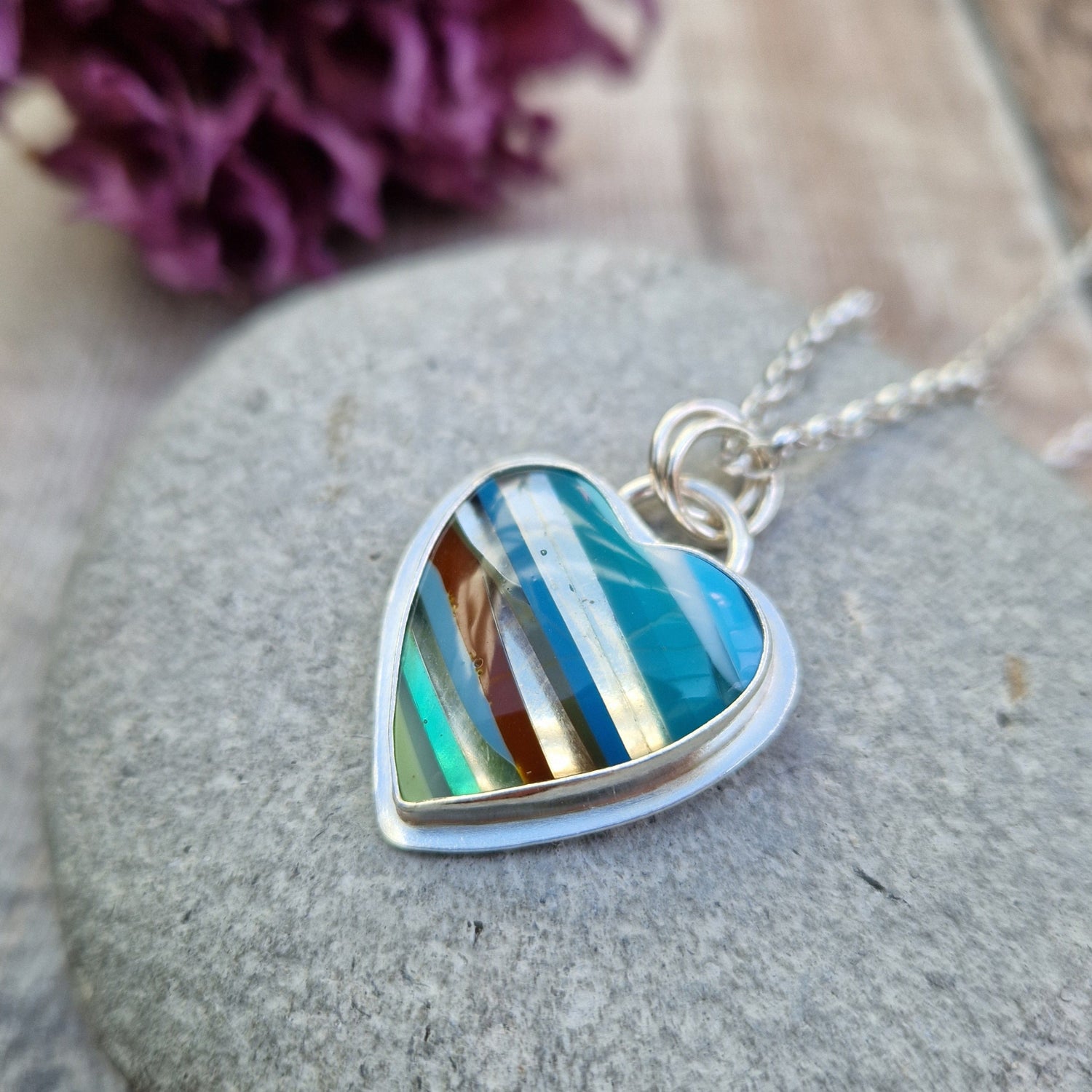 Surfite Jewellery shown displayed on a grey stone with dried flowers in the background.
