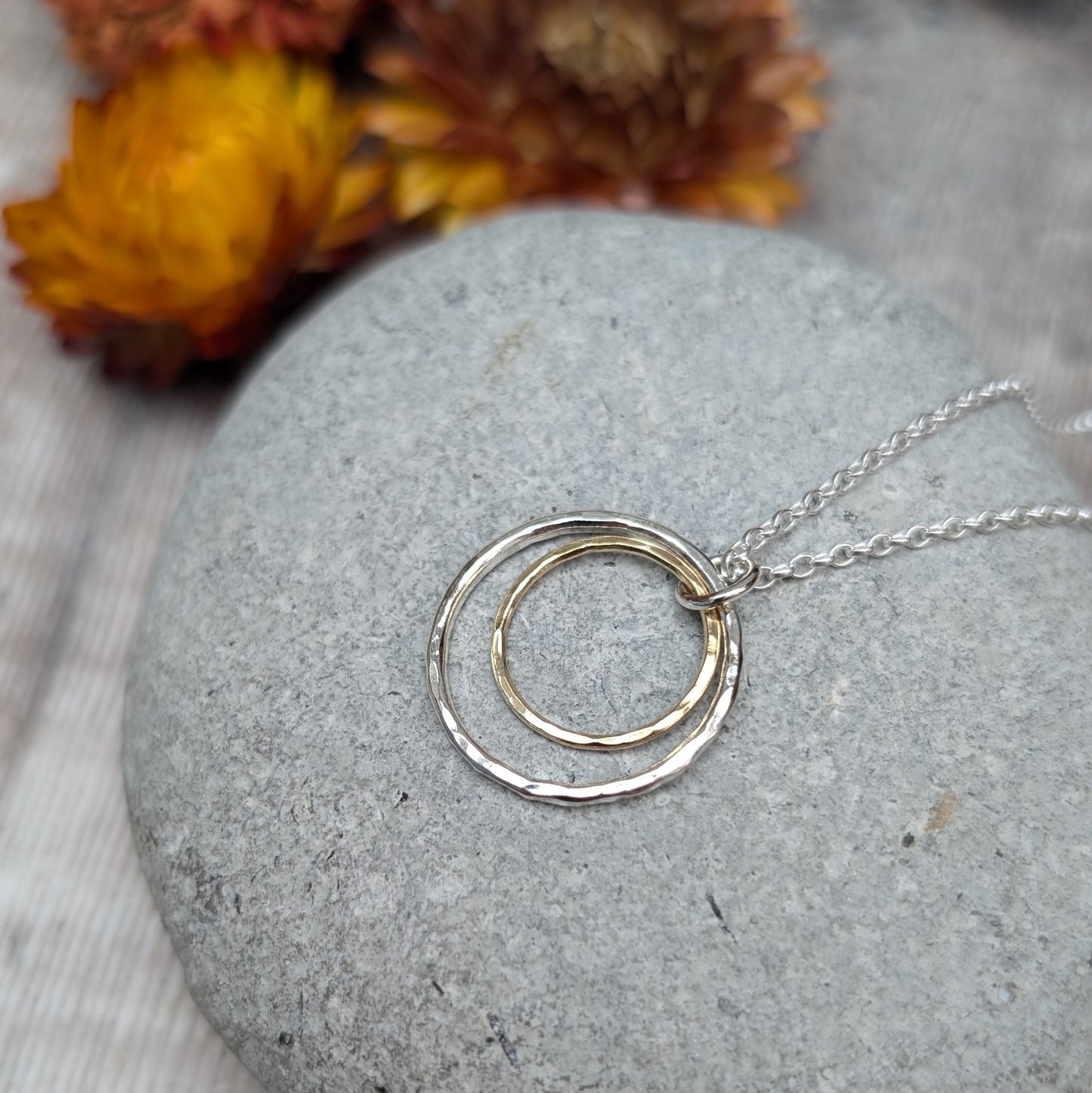 Sterling Silver open circle pendant with hammered texture approx. 20mm wide with a smaller gold open circle with hammered texture inside, attached to silver chain via small silver circle link.