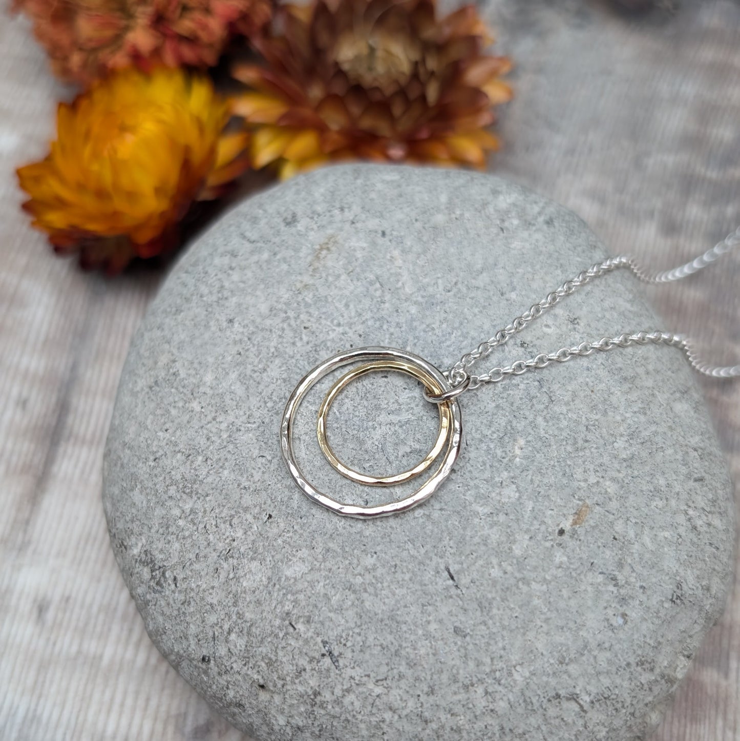 Sterling Silver open circle pendant with hammered texture approx. 20mm wide with a smaller gold open circle with hammered texture inside, attached to silver chain via small silver circle link.