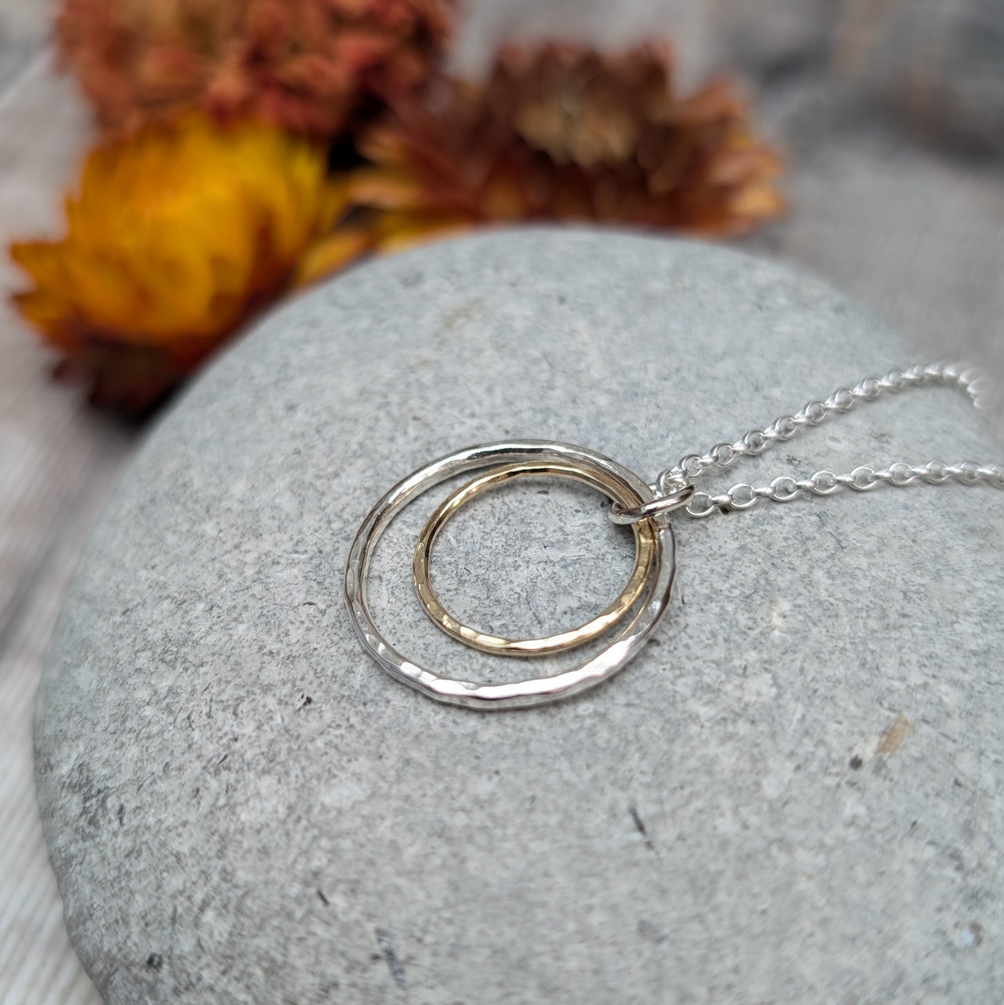 Sterling Silver open circle pendant with hammered texture approx. 20mm wide with a smaller gold open circle with hammered texture inside, attached to silver chain via small silver circle link.