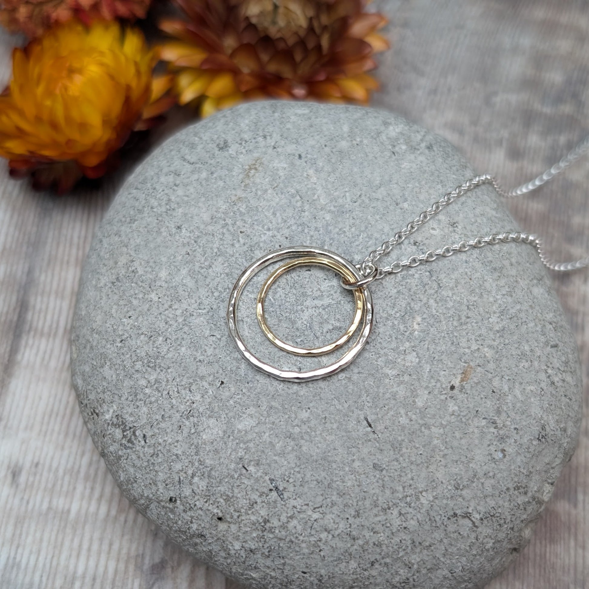 Sterling Silver open circle pendant with hammered texture approx. 20mm wide with a smaller gold open circle with hammered texture inside, attached to silver chain via small silver circle link.