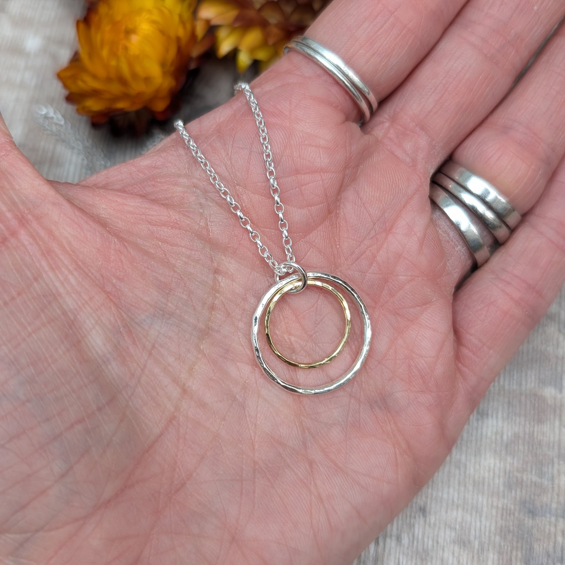 Sterling Silver open circle pendant with hammered texture approx. 20mm wide with a smaller gold open circle with hammered texture inside, attached to silver chain via small silver circle link.