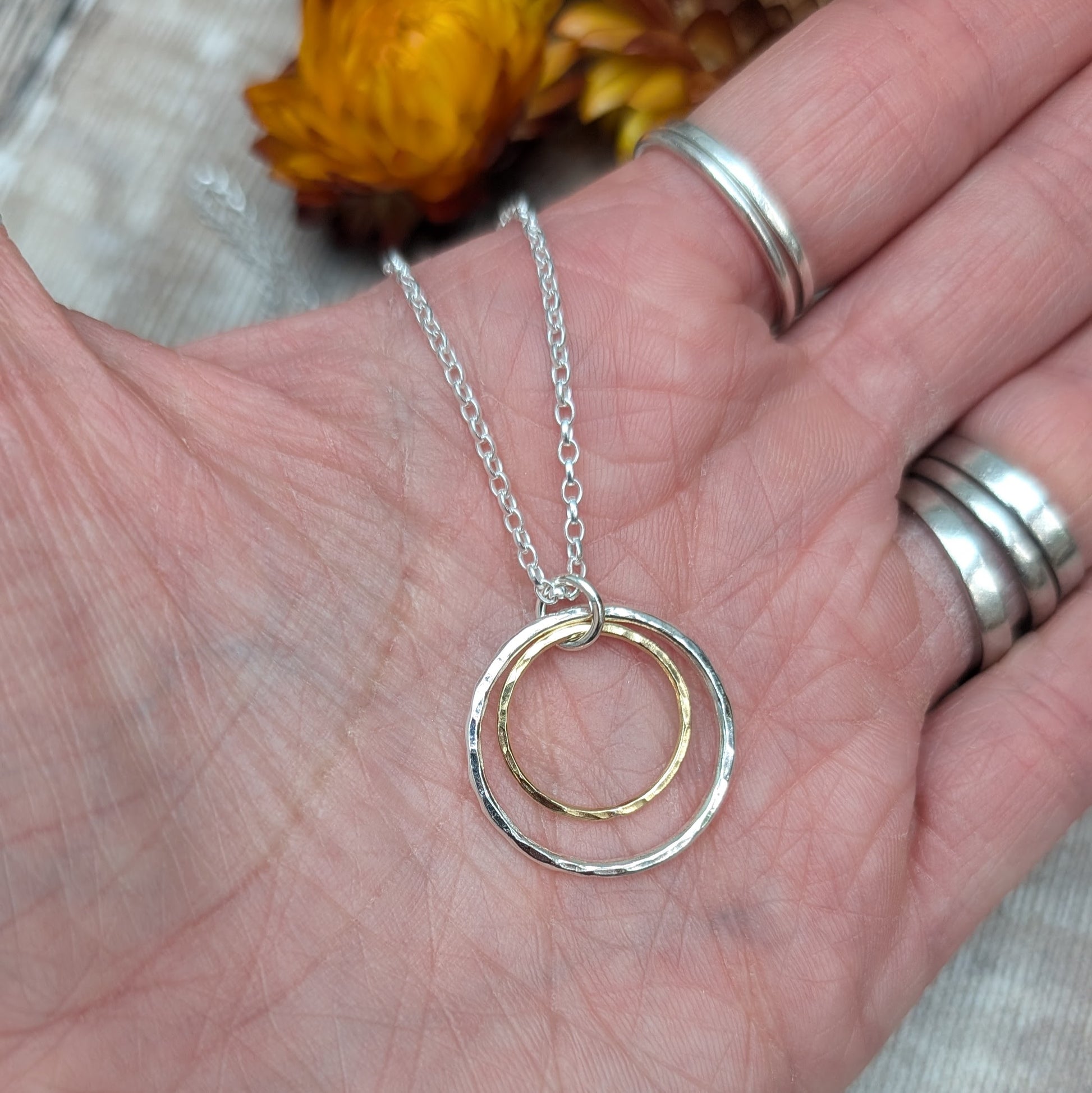 Sterling Silver open circle pendant with hammered texture approx. 20mm wide with a smaller gold open circle with hammered texture inside, attached to silver chain via small silver circle link.