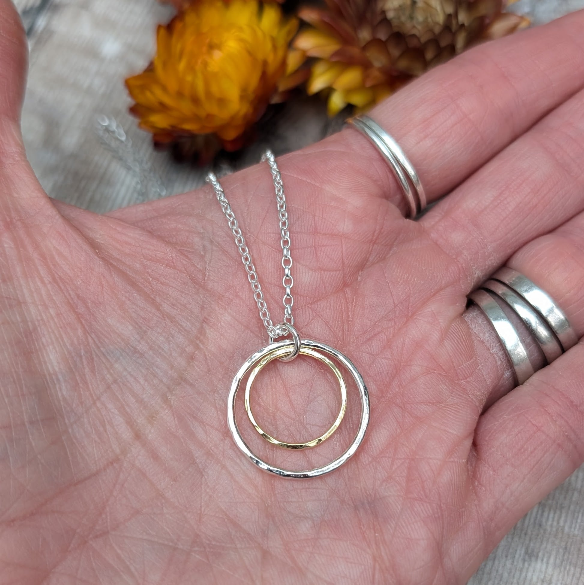 Sterling Silver open circle pendant with hammered texture approx. 20mm wide with a smaller gold open circle with hammered texture inside, attached to silver chain via small silver circle link.