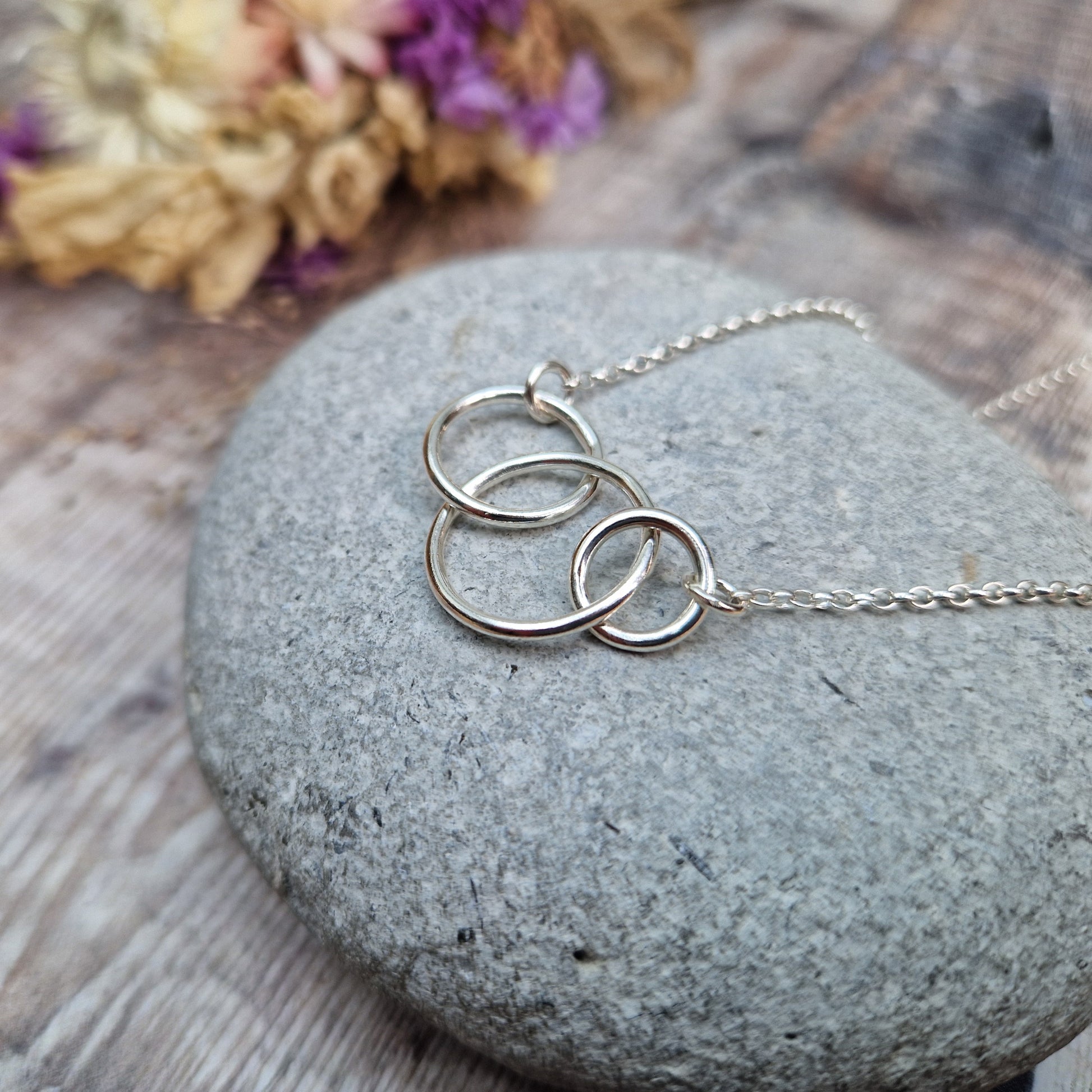 Three different sized Sterling Silver open circles linked together. Each outside circle is linked to a silver chain via small cirle links. The largest open circle is central.