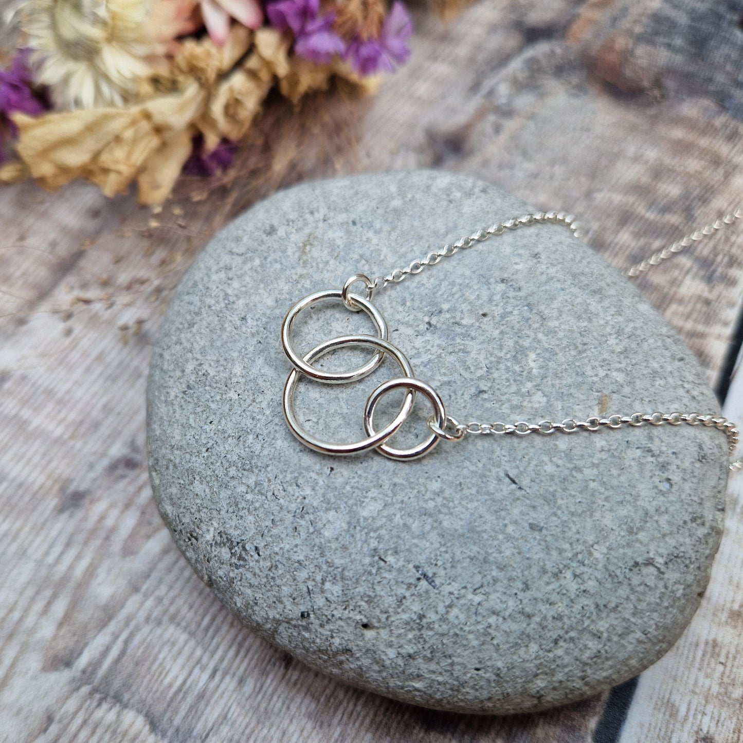 Three different sized Sterling Silver open circles linked together. Each outside circle is linked to a silver chain via small cirle links. The largest open circle is central.