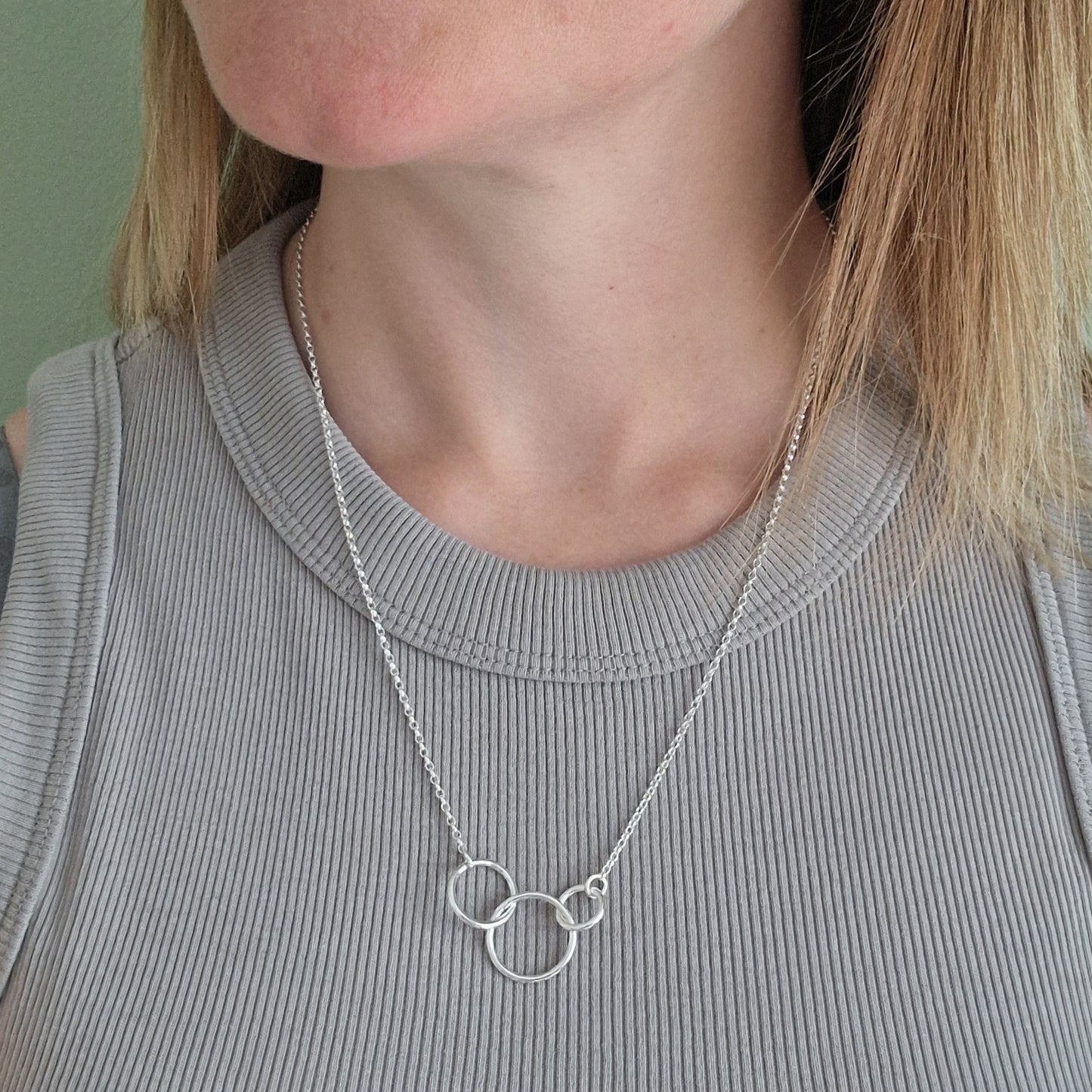 Three different sized Sterling Silver open circles linked together. Each outside circle is linked to a silver chain via small cirle links. The largest open circle is central.