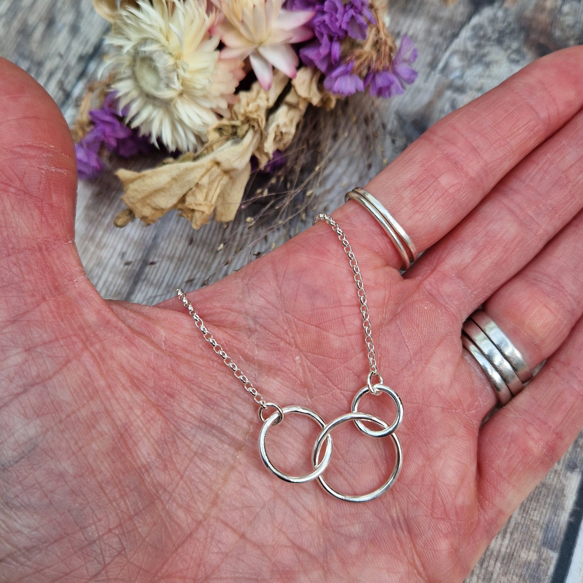 Three different sized Sterling Silver open circles linked together. Each outside circle is linked to a silver chain via small cirle links. The largest open circle is central.