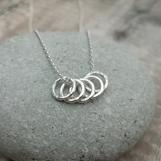 Five small Sterling Silver open circles with hammered texture finish on a silver chain.