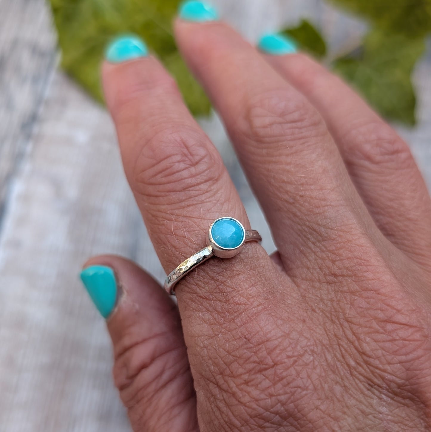 amazonite ring size R being worn on a hand, showing the handmade recycled Sterling Silver band with a round blue green Amazonite gemstone in a simple bezel setting.