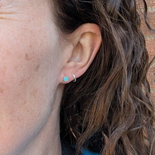 Silver amazonite studs worn in the ear, showing their small round turquoise stones against the wearer’s skin and hair.