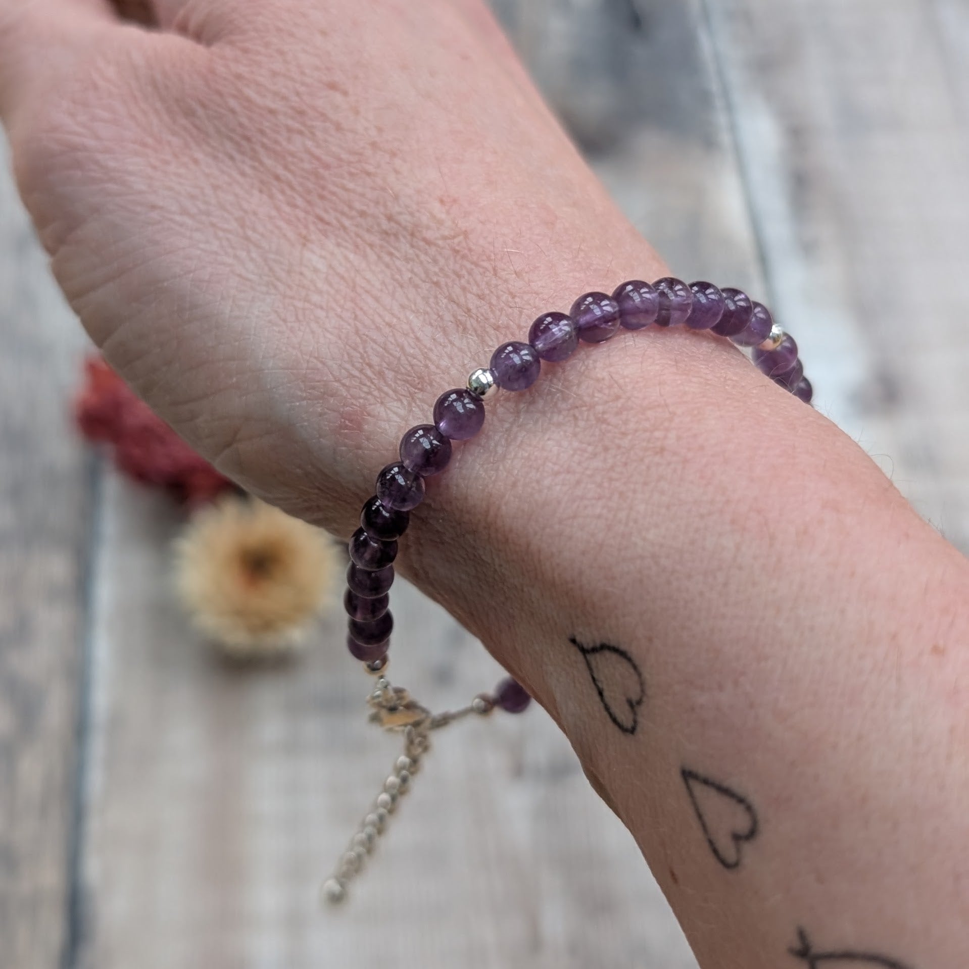 Amethyst bead bracelet worn on the wrist, showing the rich purple tones of the stones and the delicate silver detailing.