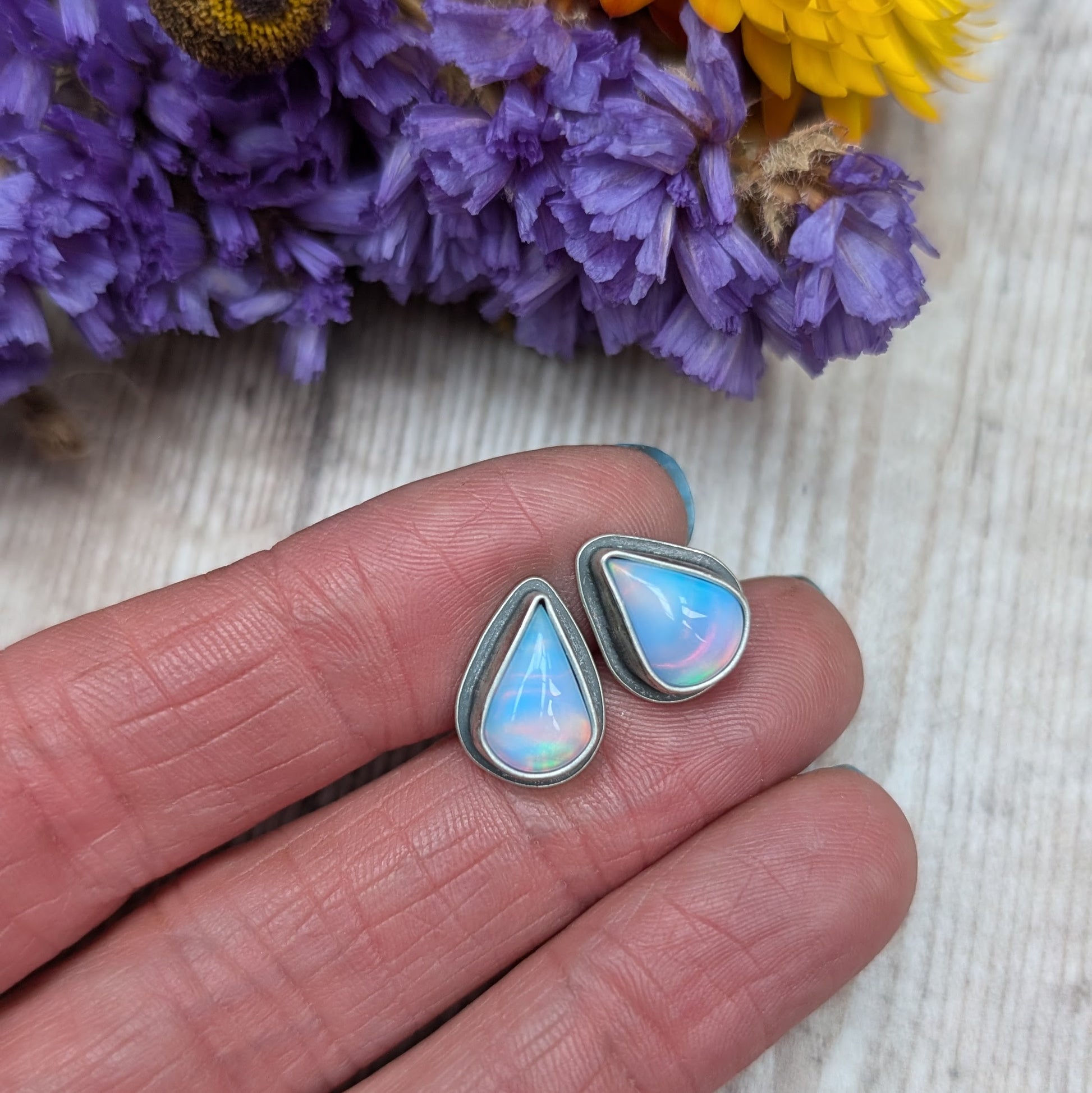 Teardrop shaped Aurora Opal with iridescent rainbow hues and smooth finish, set in simple oxidised silver bezel attached to stud bar.