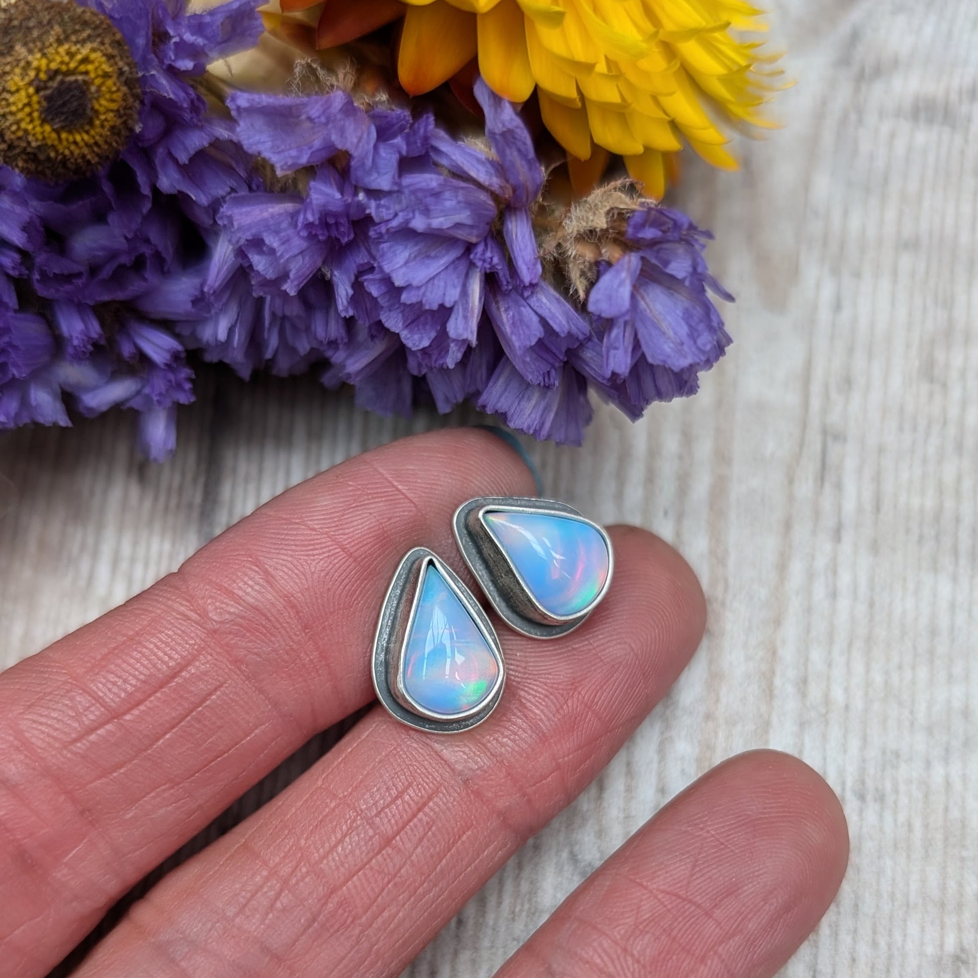 Teardrop shaped Aurora Opal with iridescent rainbow hues and smooth finish, set in simple oxidised silver bezel attached to stud bar.