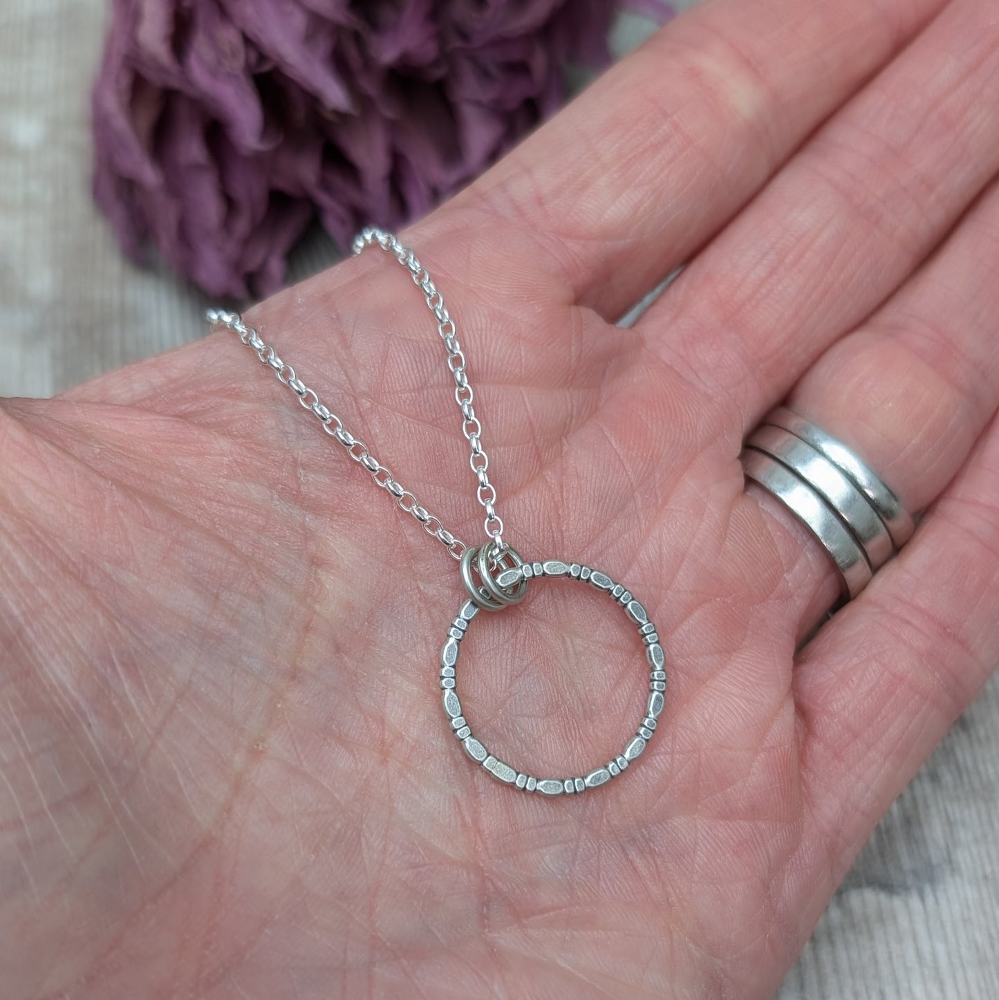 Pendant is Sterling Silver open circle made of beaded repeating pattern, suspended from silver chain via two small open circle links.