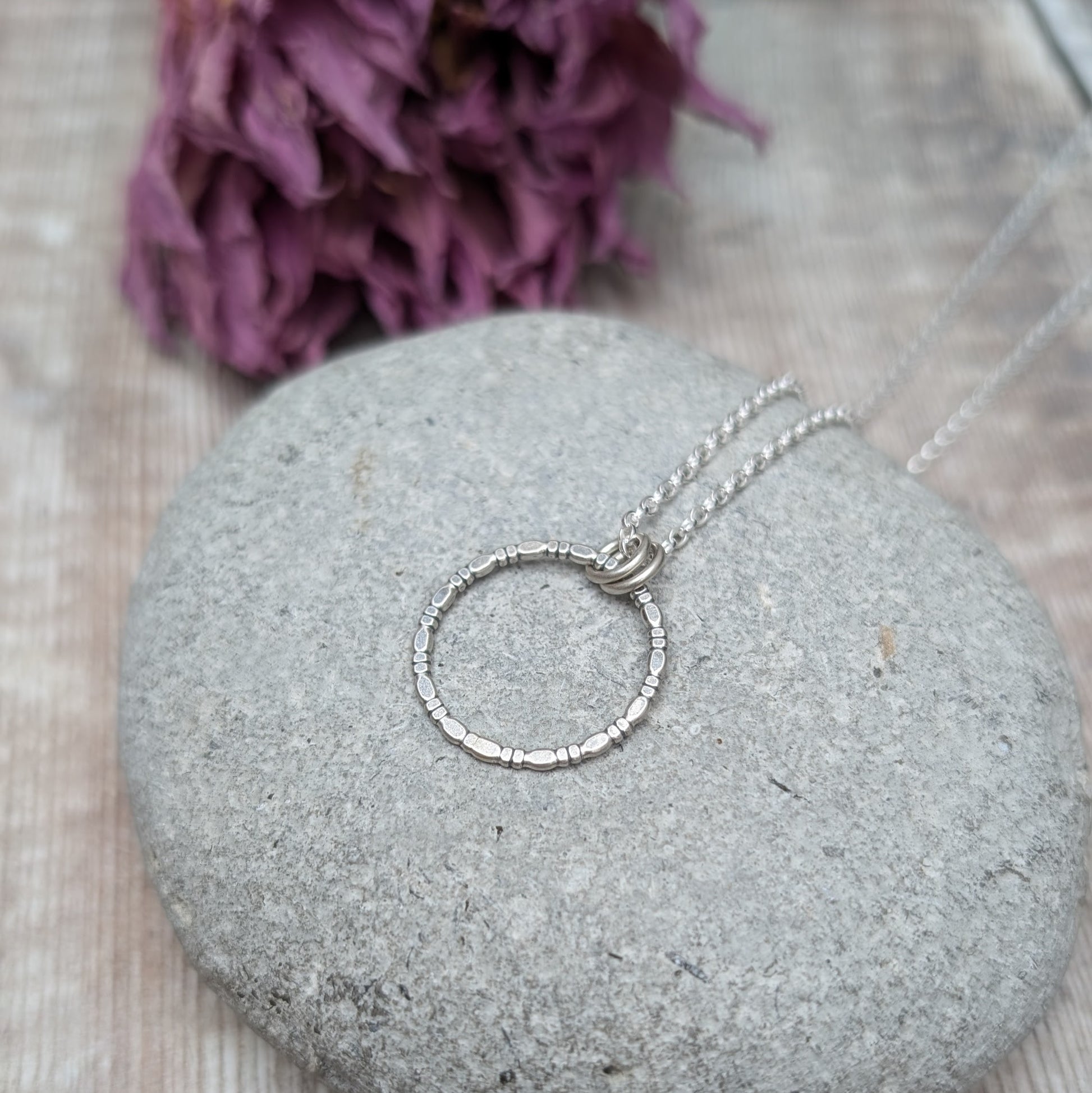 Pendant is Sterling Silver open circle made of beaded repeating pattern, suspended from silver chain via two small open circle links.