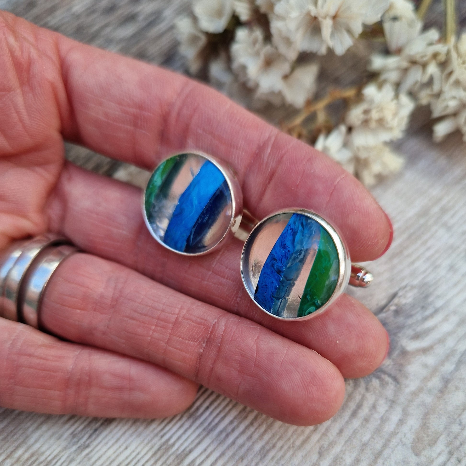 Sterling Silver round cufflinks approx. 18mm diameter each with surfite stone set in silver bezel surround. Horizonal, wide surfite stripes are green, clear, blue, clear and some black. Each surfite stone is individual.