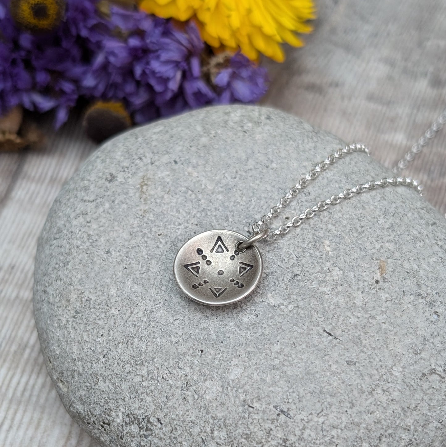 Oxidised Sterling Silver dome shaped pendant suspended from silver chain. Pendant has geometric triangular and dot patterns on the inside of the curved dome.