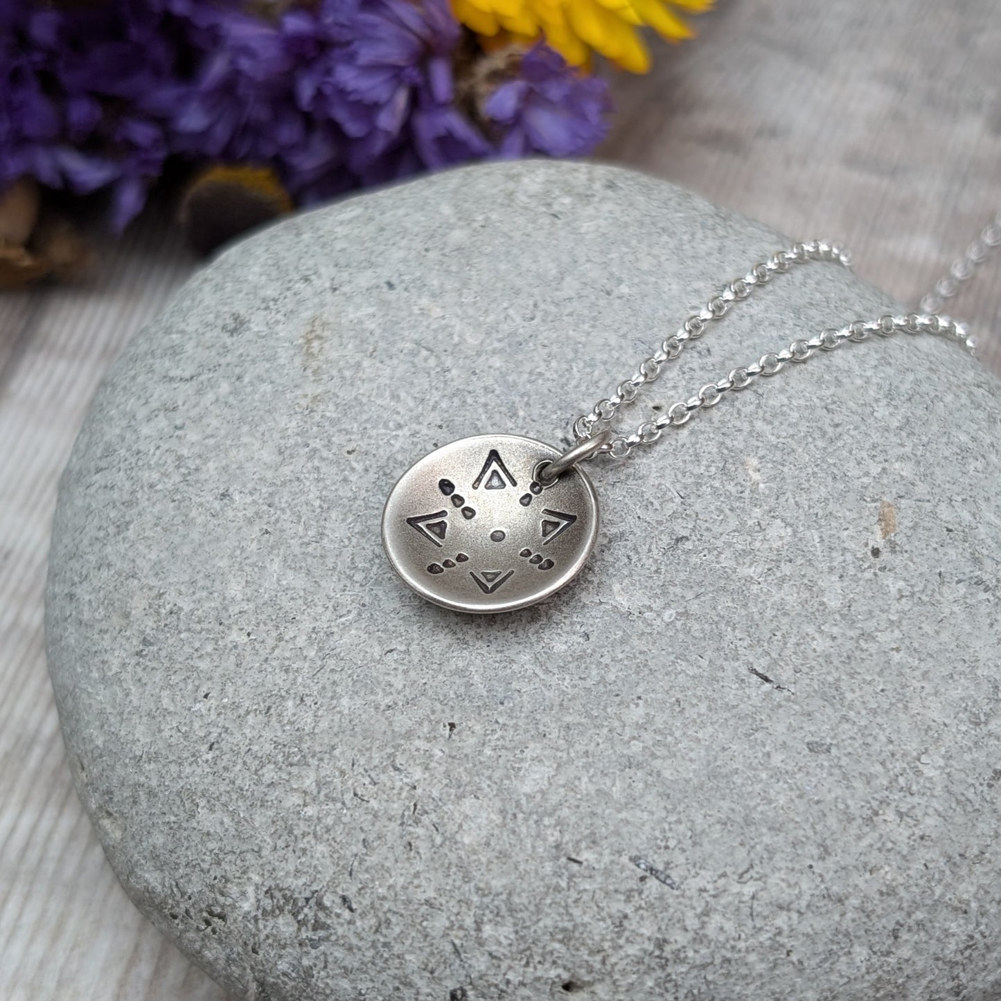 Oxidised Sterling Silver dome shaped pendant suspended from silver chain. Pendant has geometric triangular and dot patterns on the inside of the curved dome.