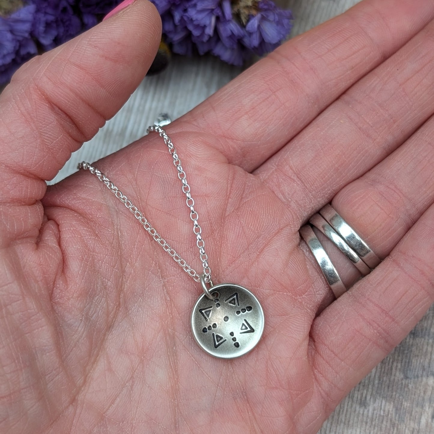 Oxidised Sterling Silver dome shaped pendant suspended from silver chain. Pendant has geometric triangular and dot patterns on the inside of the curved dome.