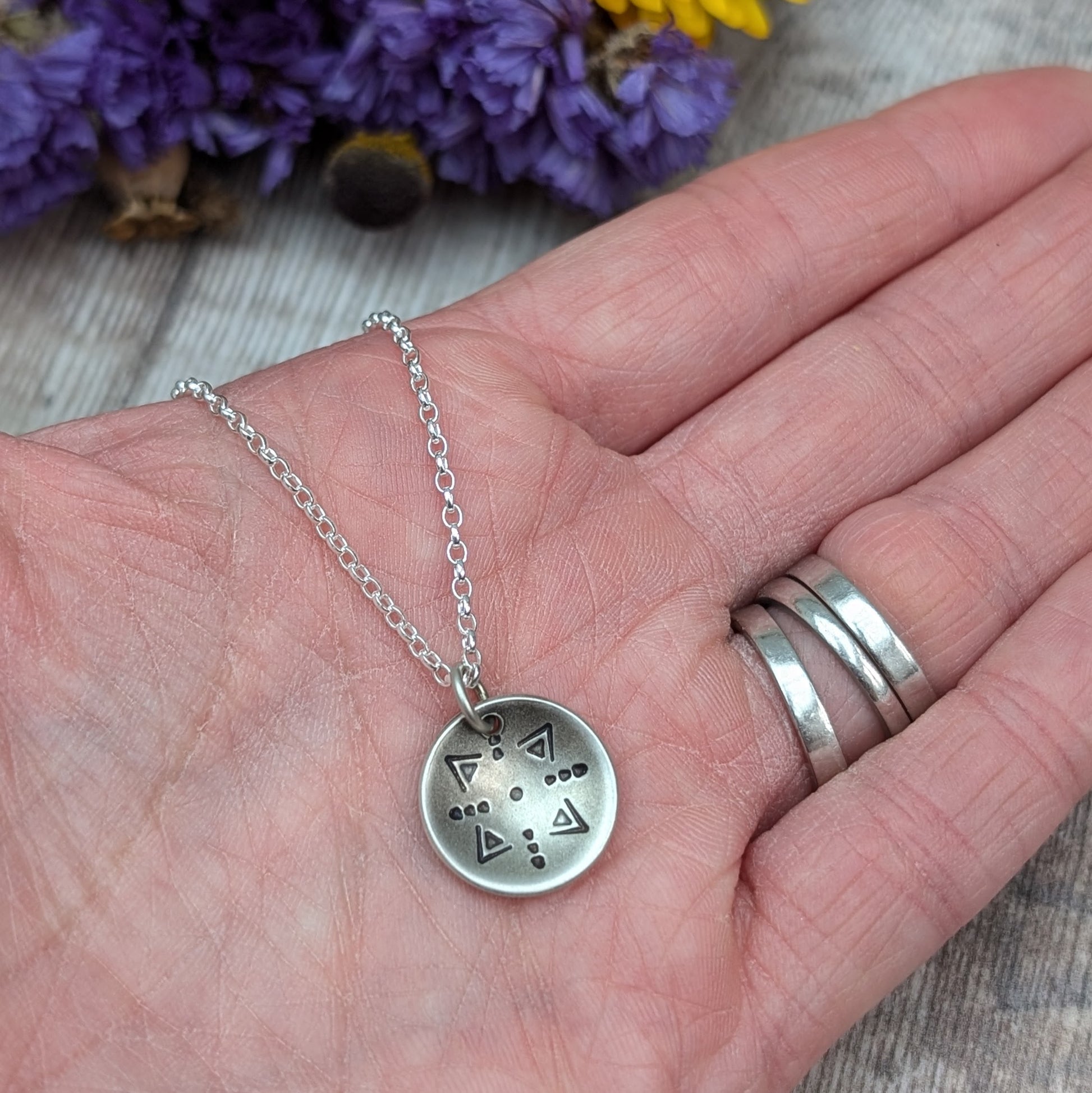 Oxidised Sterling Silver dome shaped pendant suspended from silver chain. Pendant has geometric triangular and dot patterns on the inside of the curved dome.