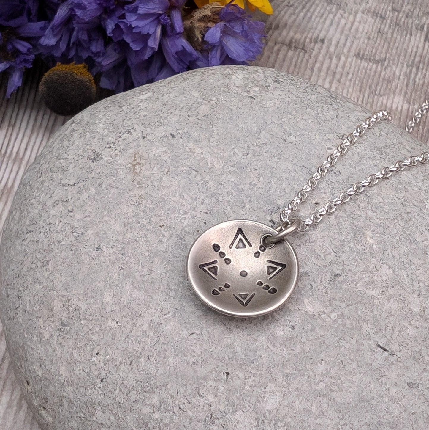 Oxidised Sterling Silver dome shaped pendant suspended from silver chain. Pendant has geometric triangular and dot patterns on the inside of the curved dome.