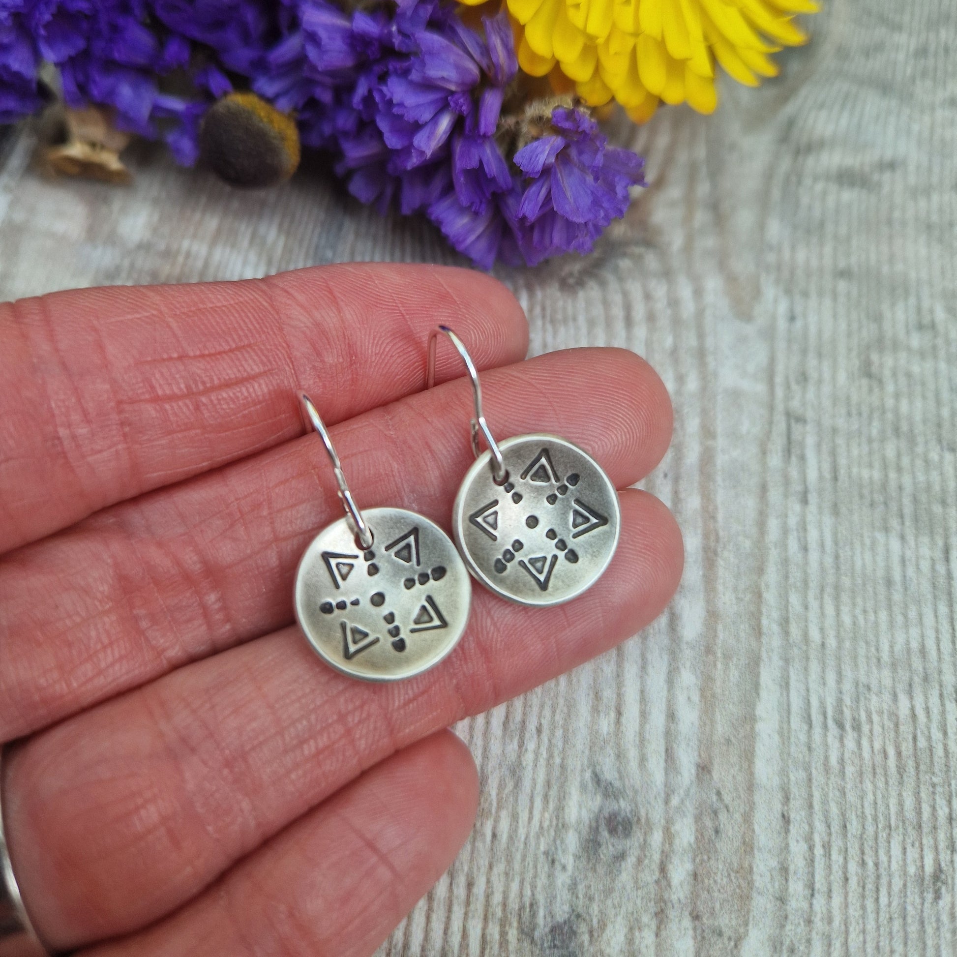 Oxidised Sterling Silver dome shaped pendant suspended from silver earring wire. Each earring pendant has geometric triangular and dot patterns on the inside of the curved dome.