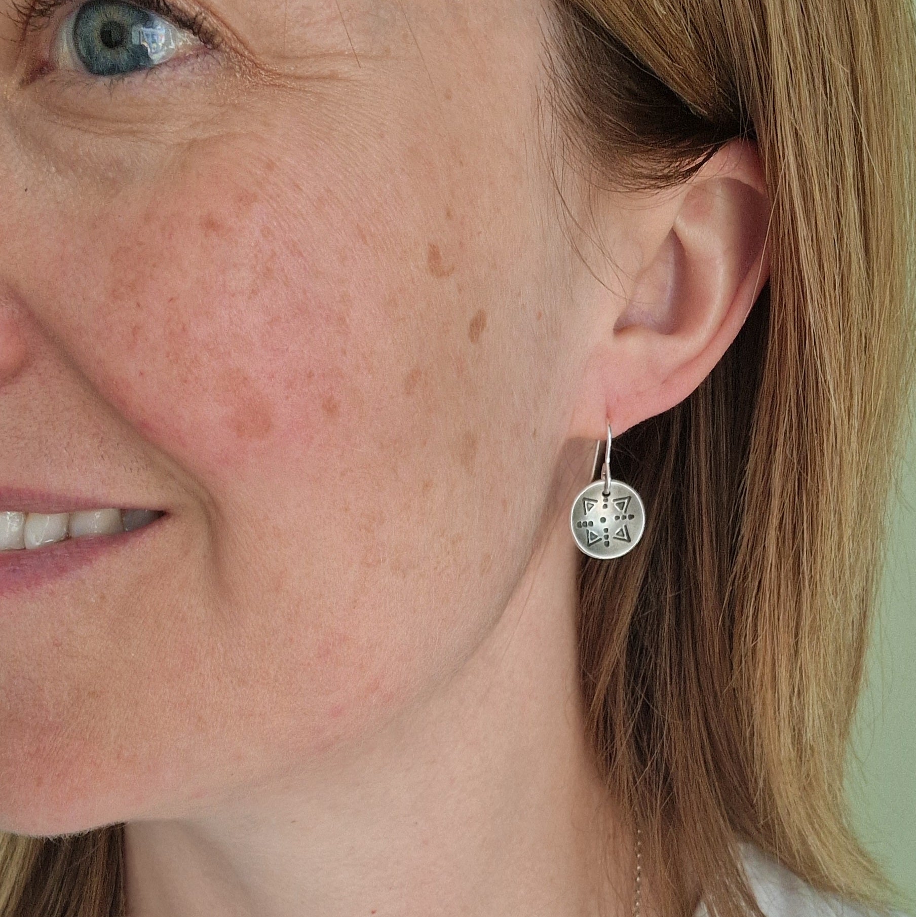 Oxidised Sterling Silver dome shaped pendant suspended from silver earring wire. Each earring pendant has geometric triangular and dot patterns on the inside of the curved dome.