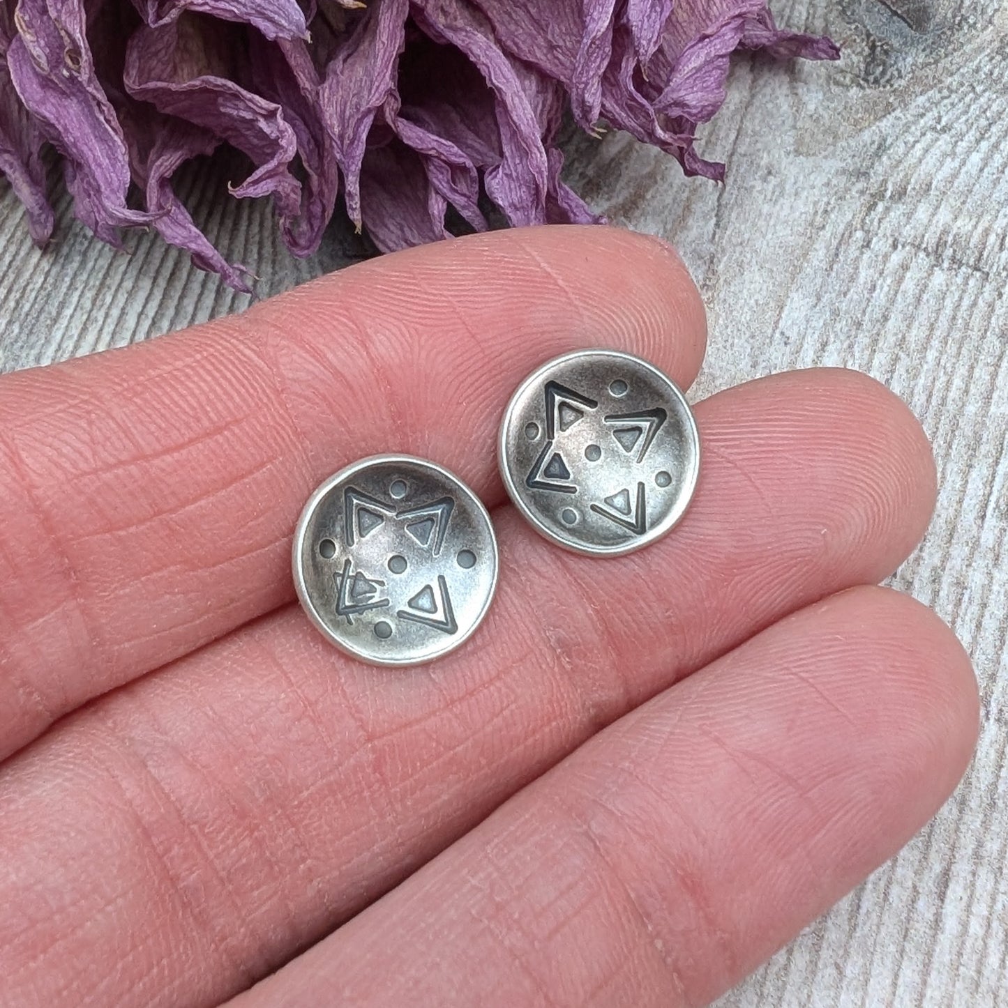 Oxidised Sterling Silver dome shaped disc attached to silver earring bar. Each earring has geometric triangular and dot patterns on the inside of the curved dome.