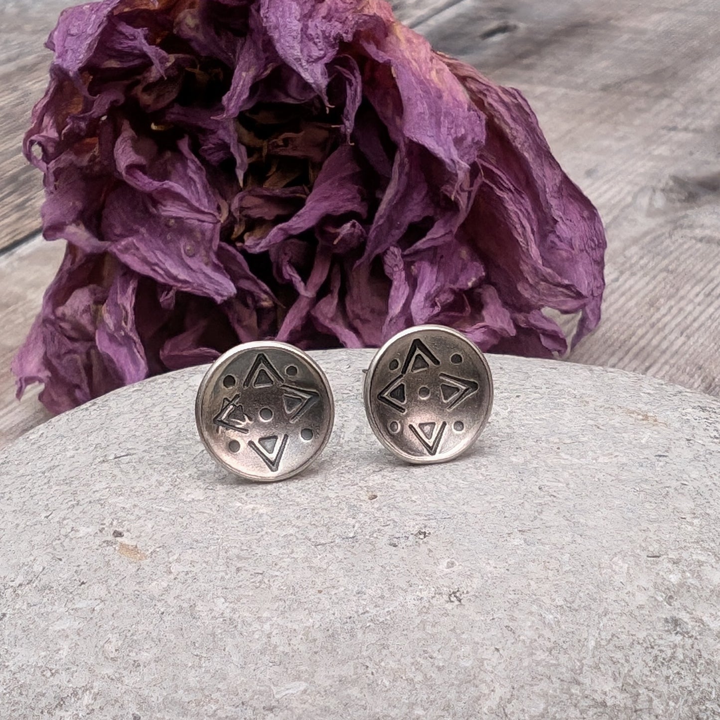 Oxidised Sterling Silver dome shaped disc attached to silver earring bar. Each earring has geometric triangular and dot patterns on the inside of the curved dome.